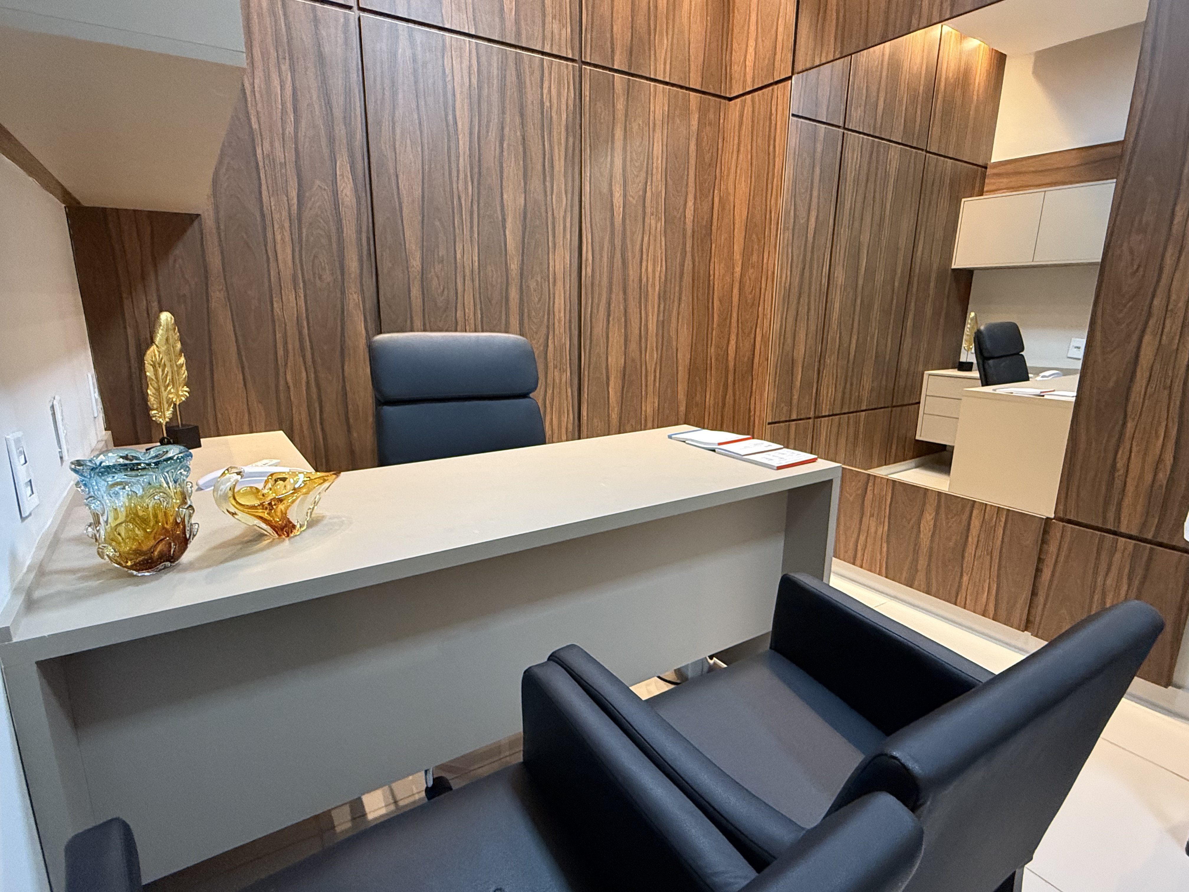 Consultório médico com mesa de trabalho e área de exames