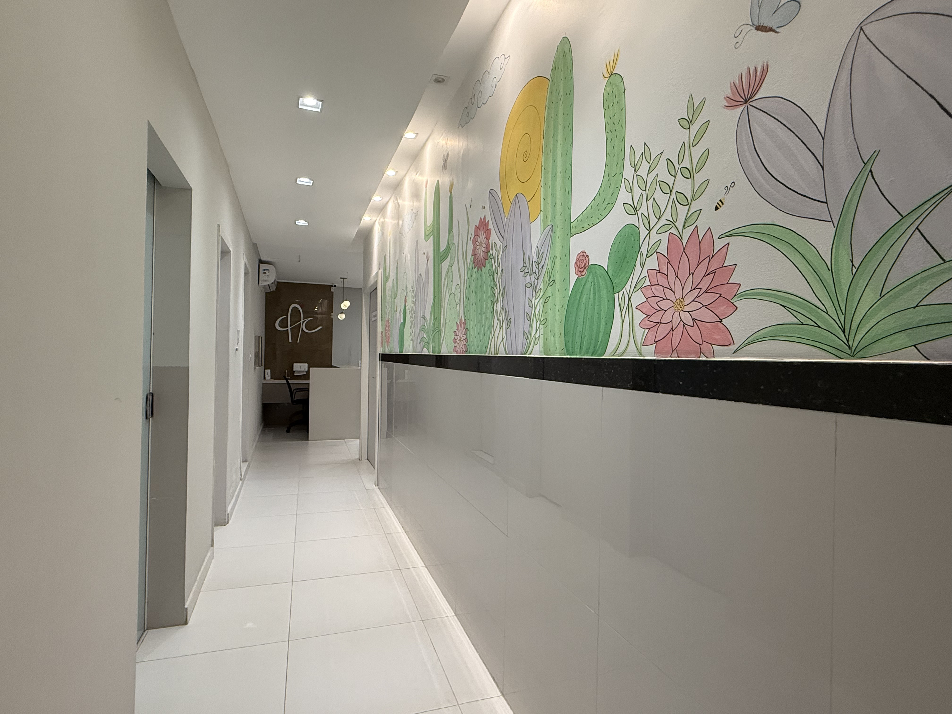 Corredor principal com mural de cactos e iluminação moderna